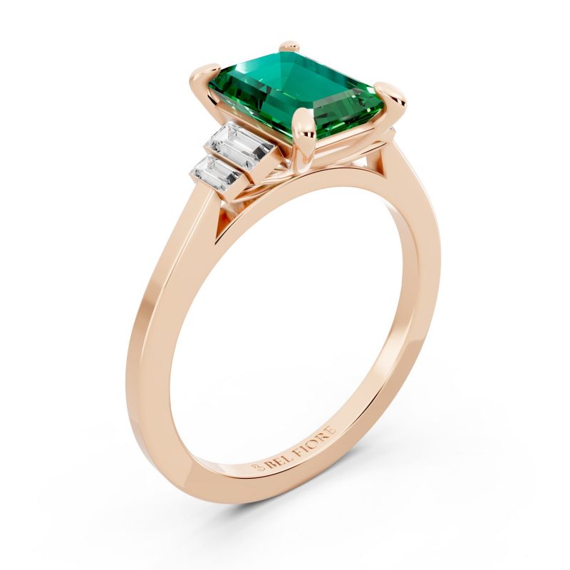 Bezel set three stone emerald engagement ring in rose gold, top view