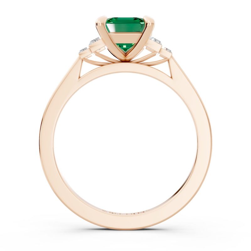 Bezel set three stone emerald engagement ring in rose gold, side profile